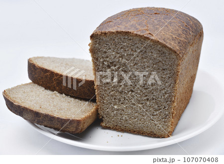 A black loaf of bread cut on a white plate. Slices of bread. Breakfast from a bun. A black loaf of bread cut on a white plate. Slices of bread. Breakfast from a bun. 107070408