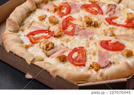Delicious hot pizza with chicken, tomatoes, cheese and bacon, with salt and spices Delicious hot pizza with chicken, tomatoes, cheese and bacon, with salt and spices 107070948