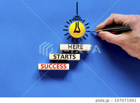 Success starts here symbol. Concept word Success starts here on beautiful wooden block. Businessman hand. Beautiful blue background. Business motivational success starts here concept. Copy space. 107071981