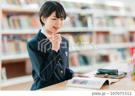 図書室で資料を広げて微笑む女子高生 107075312
