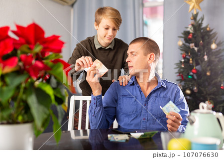 Father giving his teenage son money to celebrate christmas Father giving his teenage son money to celebrate christmas 107076630