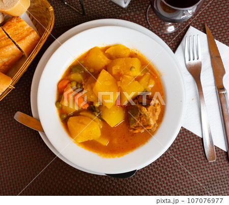 Delicious stewed pork in sauce with potatoes and vegetables. Traditional spanish dish patatas estofadas con carne 107076977