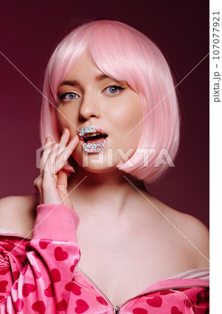 Glamorous portrait of a young woman with pink hair and glitter on her lips 107077921
