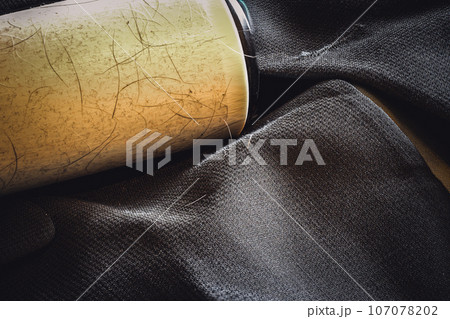 Focus stack of a lint roller resting on a dark suit jacket to remove pet animal hair. 107078202