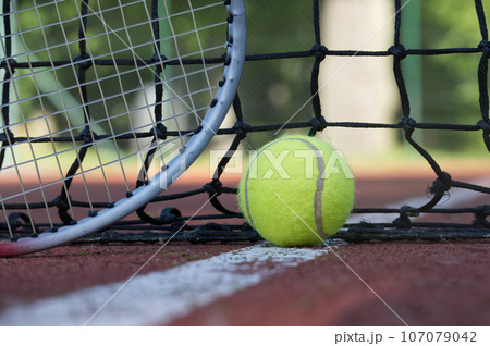 Tennis racquet and yellow tennis ball on outdoor court Tennis racquet and yellow tennis ball on outdoor court 107079042