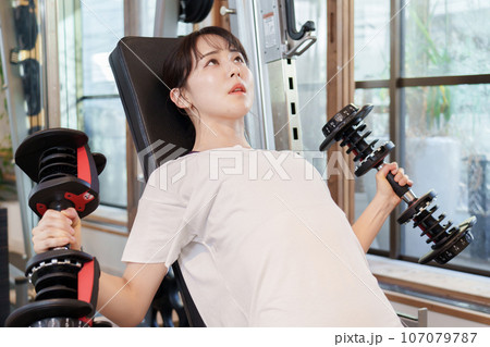 ダンベルを使って筋トレをする女性 107079787