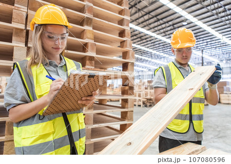 Team engineer carpenter wearing safety uniform and hard hat working holding clipboard. 107080596