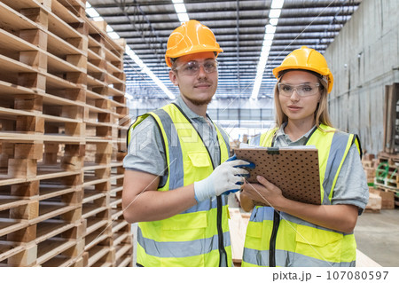 Team engineer carpenter wearing safety uniform and hard hat working holding clipboard checking. 107080597