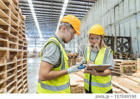 Team engineer carpenter wearing safety uniform and hard hat working holding clipboard checking. 107080598