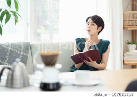 リビングで手帳を見る女性 リビングで手帳を見る女性 107081318