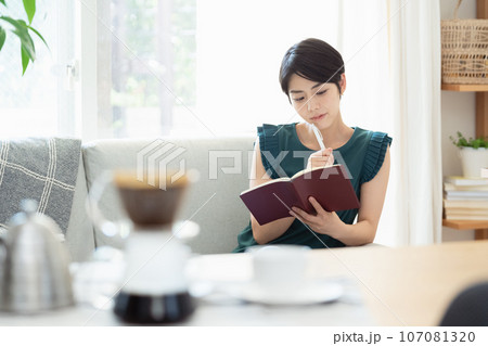 リビングで手帳を見る女性 リビングで手帳を見る女性 107081320