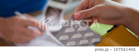 Doctor checks results of ultrasound at table with patient, who holds pills in her hand. 107081408