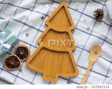 Empty christmas tree shaped wooden plate and spoon on towel background Empty christmas tree shaped wooden plate and spoon on towel background 107081524