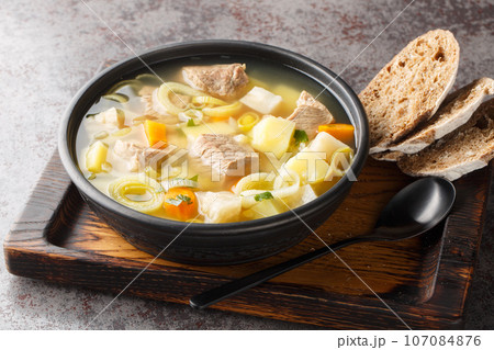 Kottsoppa soup is a meat and root vegetables include carrot, potato, celeriac, parsnip, turnip and Rutabaga close-up on a plate. Horizontal 107084876