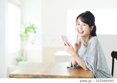 リビングでスマホを操作する若い女性 リビングでスマホを操作する若い女性 107086495