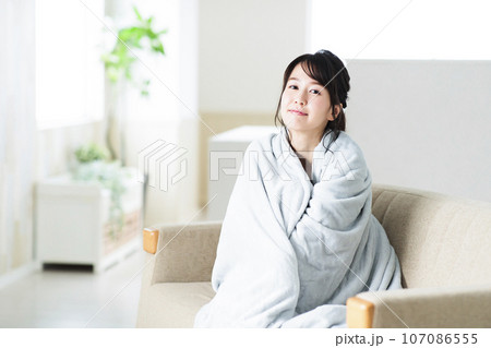 リビングのソファでブランケットを羽織る若い女性 リビングのソファでブランケットを羽織る若い女性 107086555