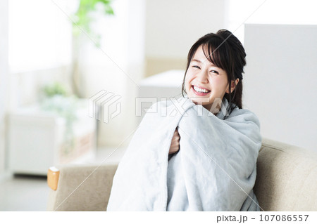 リビングのソファでブランケットを羽織る若い女性 107086557