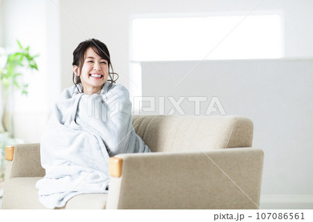 リビングのソファでブランケットを羽織る若い女性 107086561