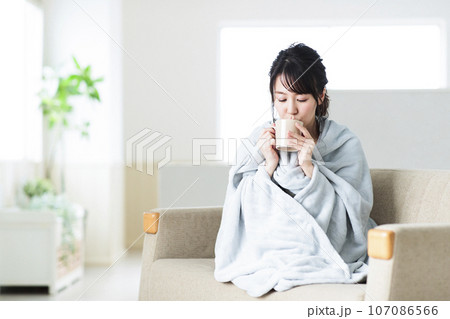 リビングのソファでブランケットを羽織る若い女性 リビングのソファでブランケットを羽織る若い女性 107086566