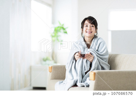 リビングのソファでブランケットを羽織る若い女性 107086570