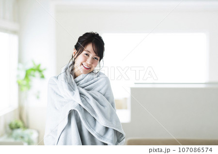 リビングでブランケットを羽織る若い女性 107086574
