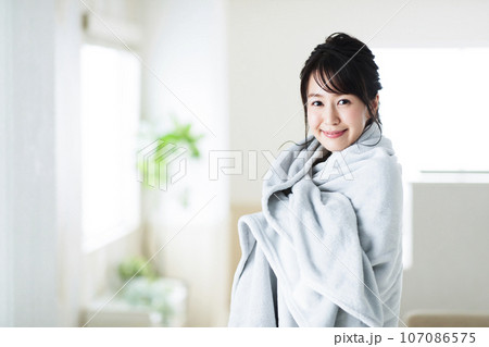 リビングでブランケットを羽織る若い女性 リビングでブランケットを羽織る若い女性 107086575