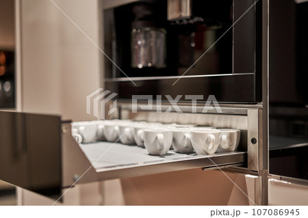 Cabinets for heating dishes. Glasses, dishes and bowls in a cabinet in a kitchen. Kitchen storage organization. Details of the interior of the kitchen in the house. Cabinets for heating dishes. Glasses, dishes and bowls in a cabinet in a kitchen. Kitchen storage organization. Details of the interior of the kitchen in the house. 107086945
