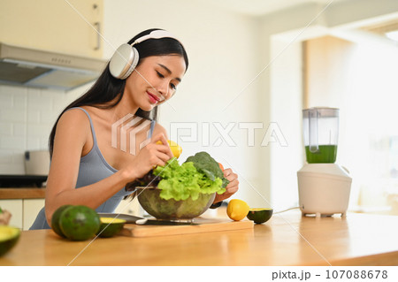 Portrait of slim asian woman with fresh vegetable preparing healthy, vegetarian food in kitchen at home. Healthy lifestyle concept Portrait of slim asian woman with fresh vegetable preparing healthy, vegetarian food in kitchen at home. Healthy lifestyle concept 107088678
