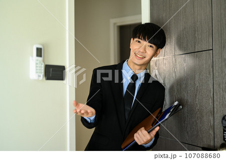 Confident male realtor showing new house and smiling to camera. Real estate, loan and property investment concept Confident male realtor showing new house and smiling to camera. Real estate, loan and property investment concept 107088680