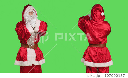 Impatient santa claus in suit checking time on wristwatch while he stands over greenscreen backdrop. Young adult dressed in festive winter character costume waiting for something, xmas spirit. Impatient santa claus in suit checking time on wristwatch while he stands over greenscreen backdrop. Young adult dressed in festive winter character costume waiting for something, xmas spirit. 107090187