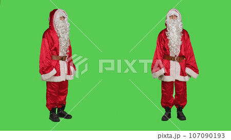 Father christmas disappointment, saying no and showing disagreement. Young man portraying santa claus with costume acting displeased and frustrated, does dislike gesture on greenscreen. 107090193