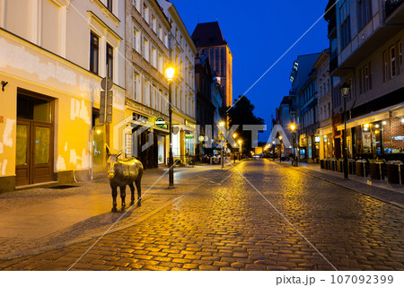 2022-07-04. Old bronze sculpture of a donkey on the street in the historical district of Torun. 107092399