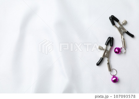 Erotic nipple clips on a light background. Erotic nipple clips on a light background. 107093578