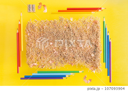 Coloured pencils and pencil shaving and sawdust on yellow background. Place for writing. School Coloured pencils and pencil shaving and sawdust on yellow background. Place for writing. School 107093904