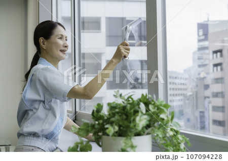 オフィスで窓の掃除をするシニア女性清掃員 オフィスで窓の掃除をするシニア女性清掃員 107094228