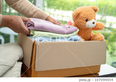 Donation box with used clothes and doll at home to support help for poor people in the world. Donation box with used clothes and doll at home to support help for poor people in the world. 107094854