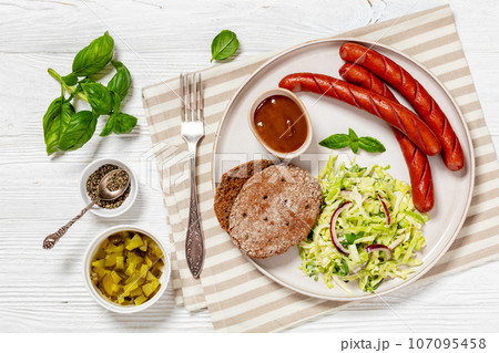 sausages with coleslaw salad, bbq sauce on plate 107095458