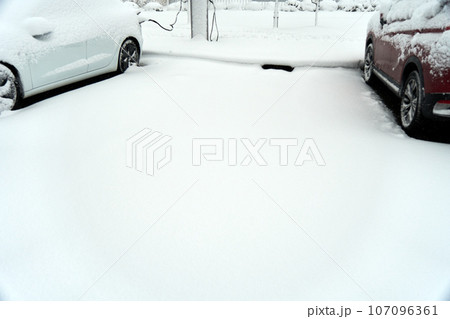 雪の中充電の為に駐車をしていたら雪に埋もれてしまった電気自動車の隣の駐車スペース 107096361