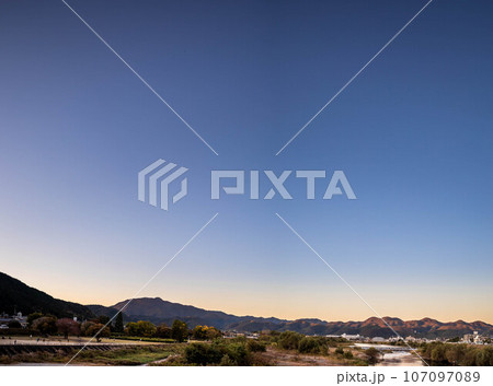 京都盆地の秋、松尾橋から眺めた秋晴れの桂川サイクルロード、北東の澄んだ夕空 107097089