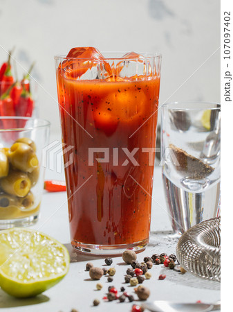 Cocktail bloody mary with pepper,lime,bar shaker and strainer on light board.Macro Cocktail bloody mary with pepper,lime,bar shaker and strainer on light board.Macro 107097402
