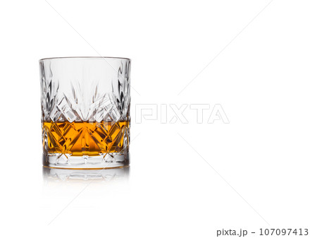 Scotch whiskey in crystal elegant glass on white background with reflection. 107097413