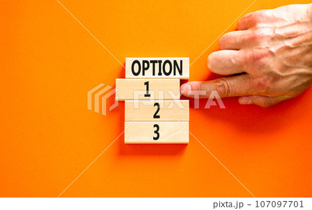 Time to option 1 symbol. Concept word Option 1 2 3 on wooden block. Businessman hand. Beautiful orange table orange background. Business planning and time to option 1 concept. Copy space. 107097701