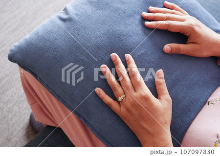 women holding a orange color pillow while sit on a sofa , women holding a orange color pillow while sit on a sofa , 107097830