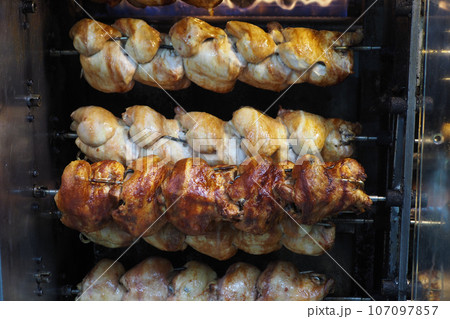 Roasted chickens grilled on the fire of the barbecue Roasted chickens grilled on the fire of the barbecue 107097857
