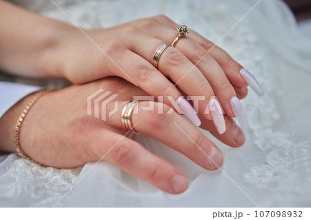 Young married couple holding hands, ceremony wedding day Young married couple holding hands, ceremony wedding day 107098932