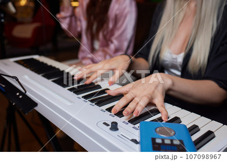Closeup of female hands on an electronic piano. A laptop on a keyboard instrument. Closeup of female hands on an electronic piano. A laptop on a keyboard instrument. 107098967