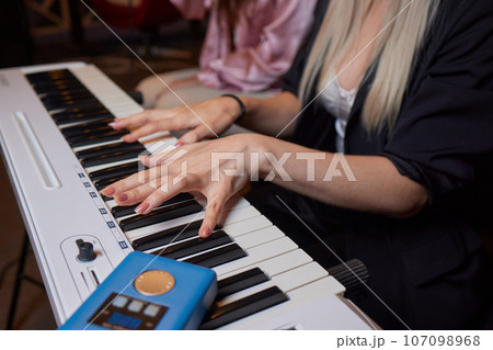 Closeup of female hands on an electronic piano. A laptop on a keyboard instrument. 107098968