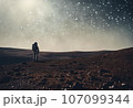Astronaut on an icy rocky surface with the sky filled with stars and galaxies, AI-generated 107099344