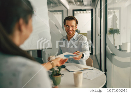 Two business colleagues analysts working with documents together sitting in office. Teamwork concept 107100243