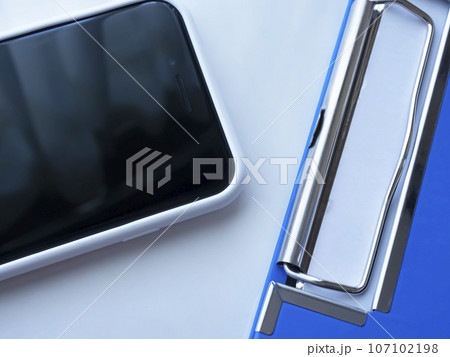 テーブルに置かれたバインダーとスマートフォン テーブルに置かれたバインダーとスマートフォン 107102198